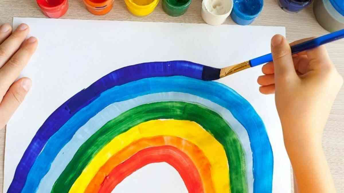 A child working on a watercolour painting with arts and crafts supplies at home.