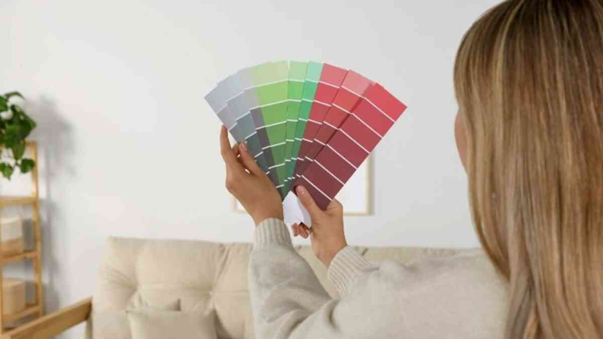 A woman choosing the best paint colours in NZ after learning about these tips.